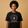Woman with a natural afro wearing the black Mwinda tee, ivory lamp flame on an indigo disc, The Twelve Flames collection by Bana Bilaka