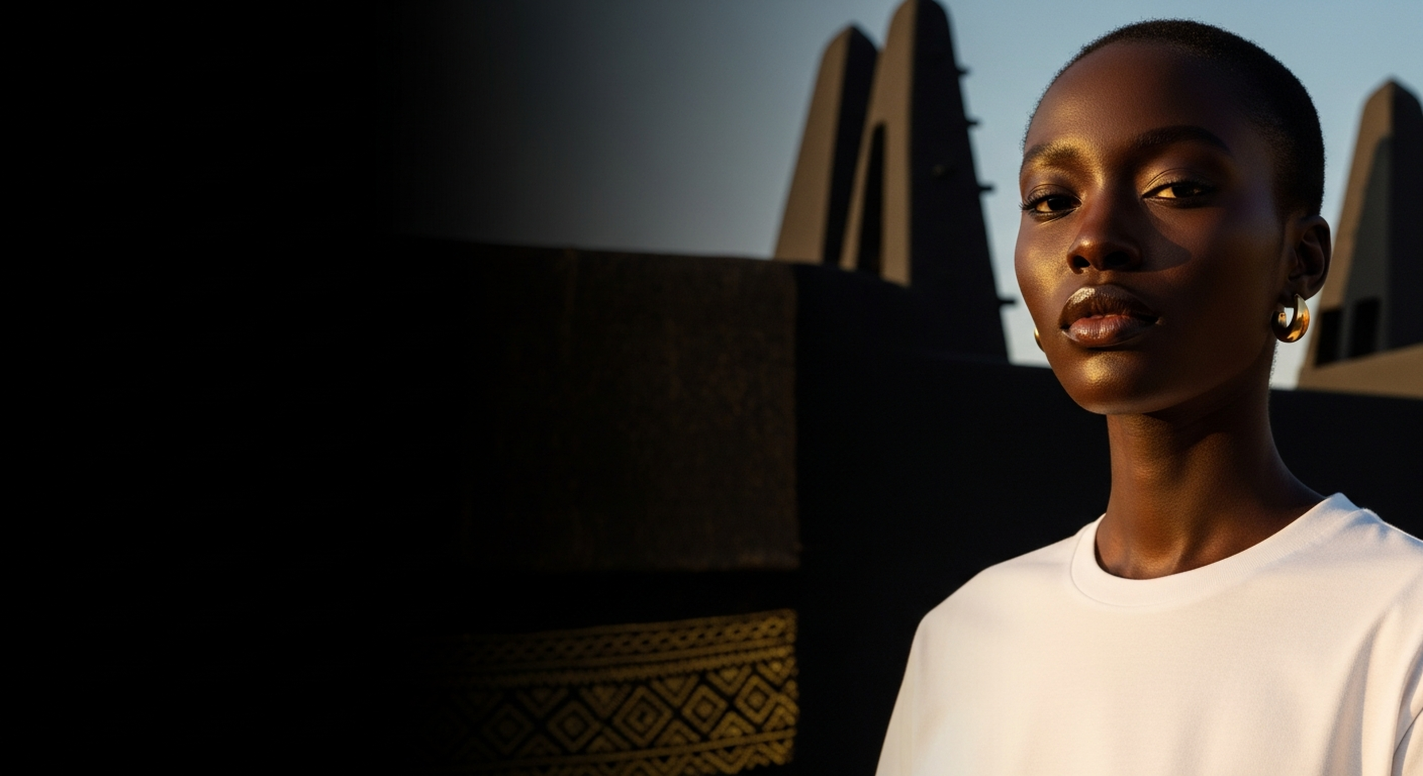 Bana Bilaka hero banner — Wear the wisdom of a continent, West African woman in white tee at golden hour