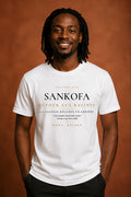 Bana Bilaka Sankofa — premium white organic cotton men's tee worn by a Black man with dreadlocks, editorial portrait