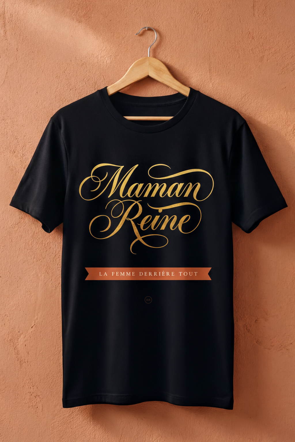 Black Maman Reine tee on a wooden hanger against a terracotta wall, Essentials gift line by Bana Bilaka