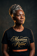 Woman in her fifties with a silver-streaked locs updo wearing the black Maman Reine tee, majestic gold calligraphy above a terracotta banner, Essentials gift line by Bana Bilaka