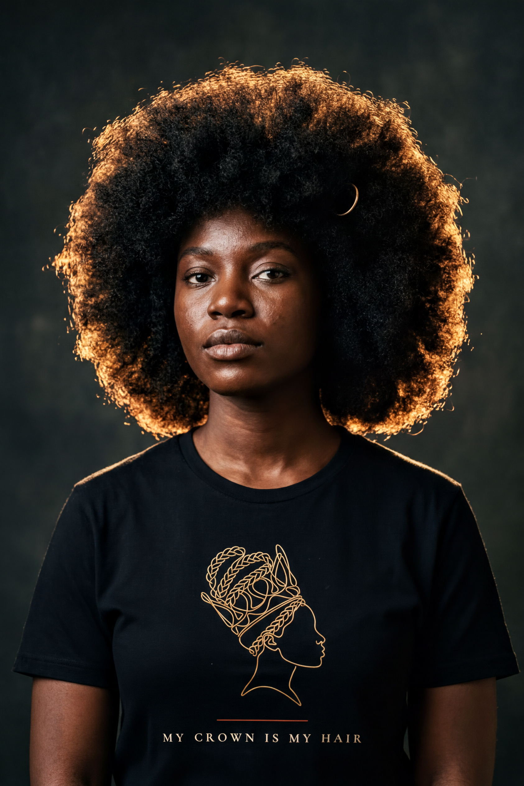 Woman with a majestic natural afro haloed by golden light wearing the black My Crown Is My Hair tee, gold line-art silhouette, Essentials collection by Bana Bilaka
