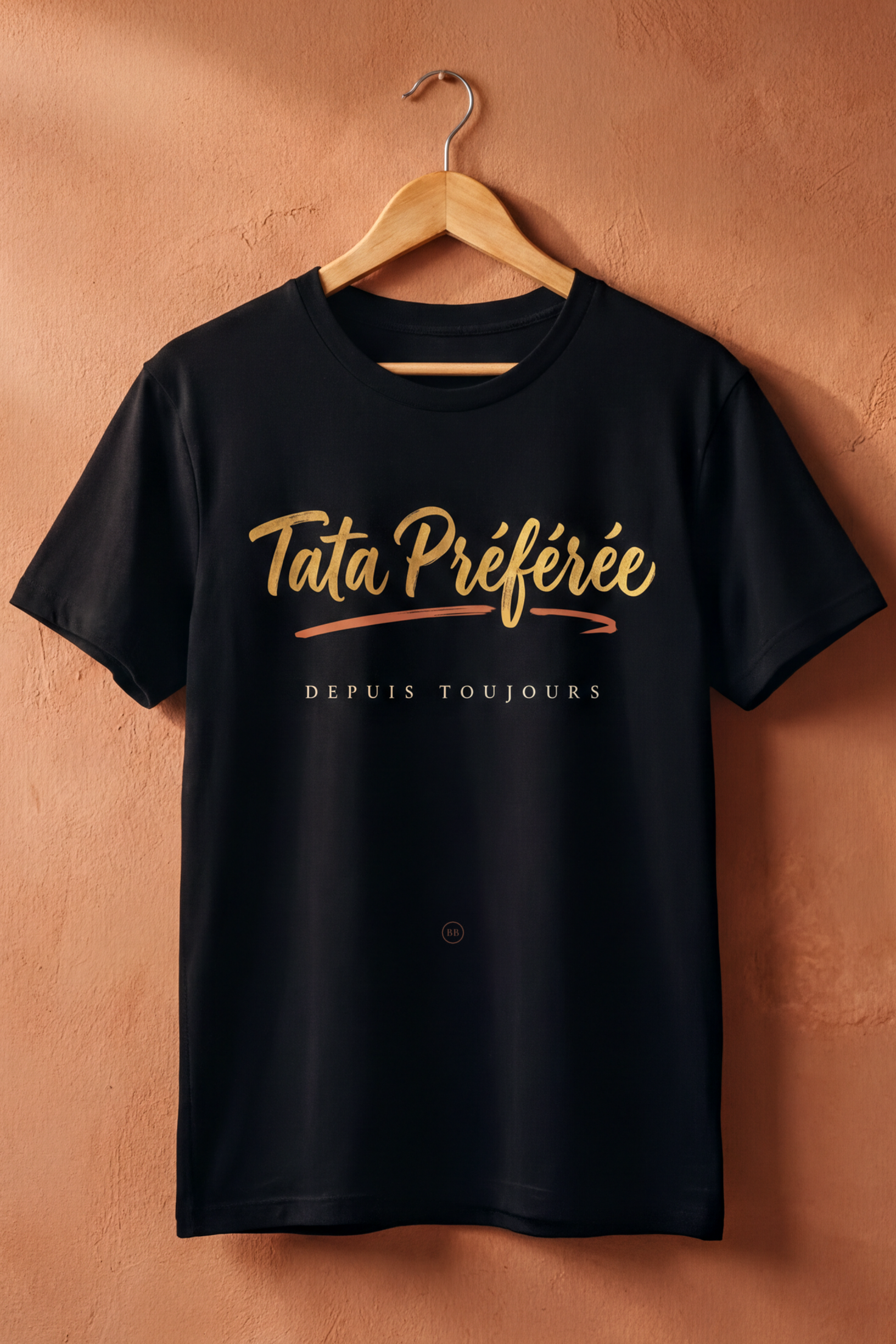Black Tata Préférée tee on a wooden hanger against a terracotta wall, Essentials gift line by Bana Bilaka