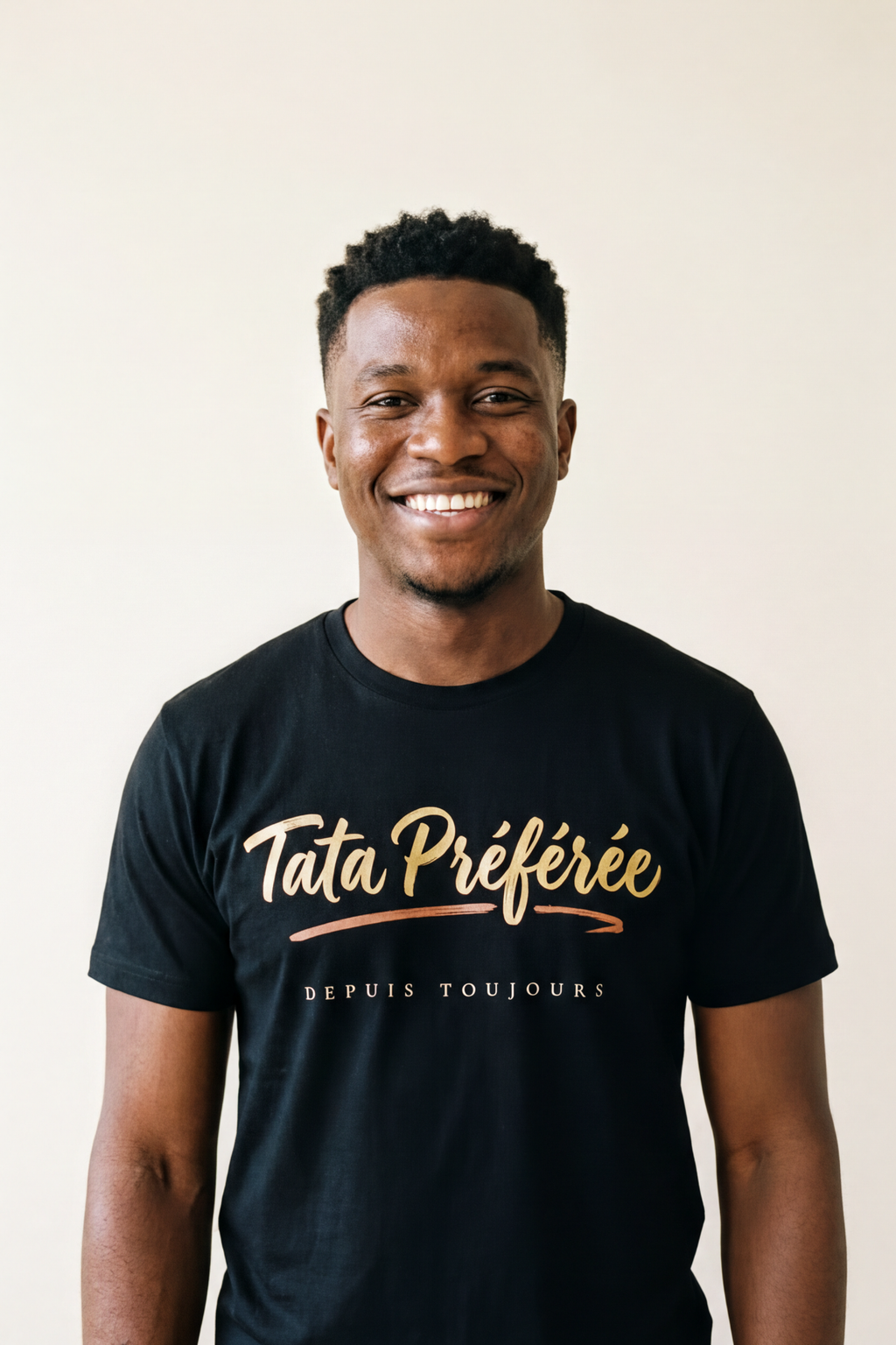 Smiling young man with short natural coils wearing the black Tata Préférée calligraphy tee, the gift from a favourite nephew, Essentials gift line by Bana Bilaka