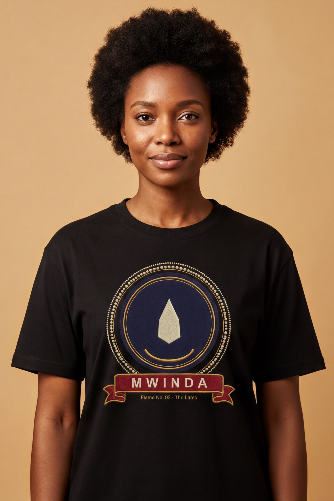 Woman with a natural afro wearing the black Mwinda tee, ivory lamp flame on an indigo disc, The Twelve Flames collection by Bana Bilaka