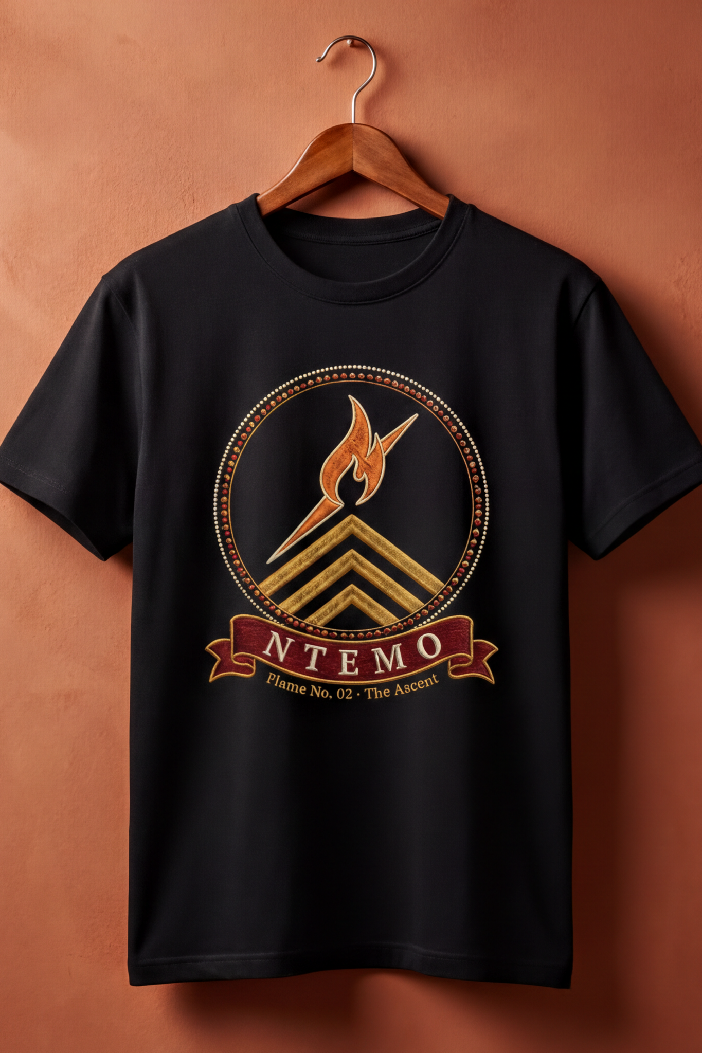 Black Ntemo tee on a wooden hanger against a terracotta wall, The Twelve Flames by Bana Bilaka