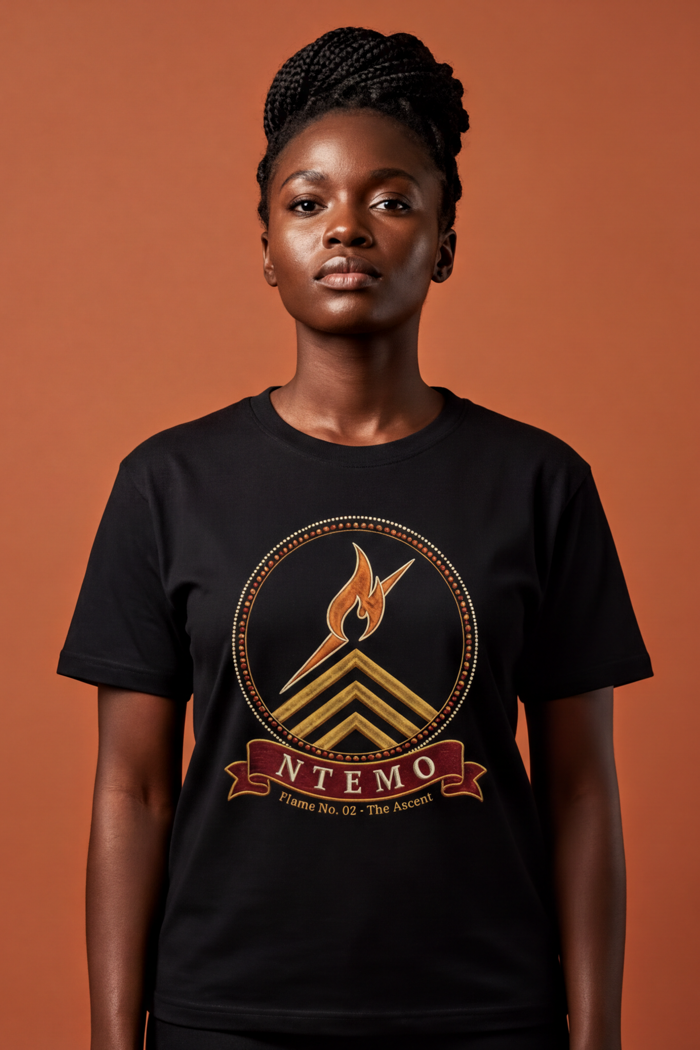Woman with a braided updo wearing the black Ntemo tee, embroidery-style flame medallion of the ascent, The Twelve Flames collection by Bana Bilaka