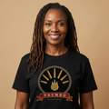 Woman with locs wearing the black Nkembo tee, deep gold flame with seven rays, The Twelve Flames collection by Bana Bilaka
