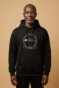 Luvemba jet black hoodie worn by a model, embroidery-style Kongo emblem printed as a chest crest, Dikenga Collection by Bana Bilaka