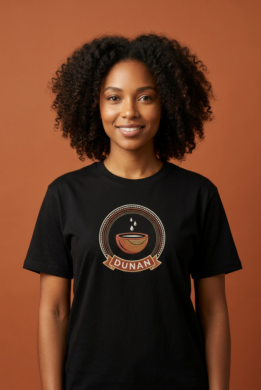 Modèle portant le tee noir Dunan, médaillon imprimé effet broderie à la calebasse d'eau, Collection Le Serment du Manden par Bana Bilaka