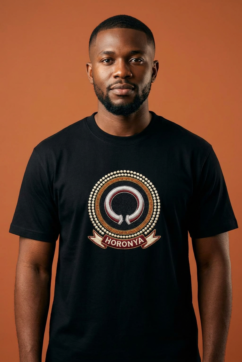 Modèle portant le tee noir Horonya, médaillon imprimé effet broderie à la manille brisée, Collection Le Serment du Manden par Bana Bilaka