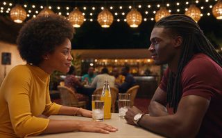 Aya et Koffi à la table d'un maquis le soir, Koffi, les chaînes invisibles